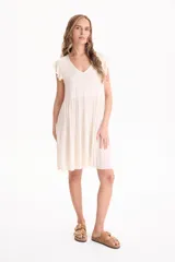 Vestido corto de viscosa color beige, sin mangas con volados en las sisas, escote en V y diseño escalonado.