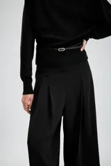 Bermuda larga de tiro medio en color beige, con diseño de pinzas frontales y costuras marcadas. Presenta un corte amplio y cierre lateral con cremallera oculta.