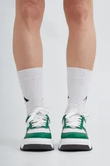 Zapatillas deportivas de cuero, combinadas en blanco y verde, con base negra.