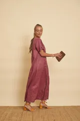 Vestido tipo túnica largo de lino, color bordo, con mangas cortas, bolsillos laterales y detalle de volados en la botonera frontal.