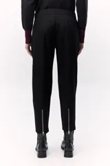 Pantalón negro estilo chino con elástico en la cintura y cierre metálico en la pierna.