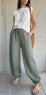 Pantalón tipo babucha de color verde militar, con cintura elástica fruncida y cordón ajustable. Cuenta con diseño amplio y puños elásticos en los tobillos.