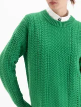 Sweater de punto color rojo con diseño de trenzas verticales y textura estructurada. Presenta cuello redondo, mangas largas y un corte holgado con terminaciones acanaladas.