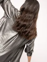 Camisa oversized con terminación metalizada color gris plomo. Tiene botones a tono en el delantero, largo por debajo de la cadera y tajos a los costados.