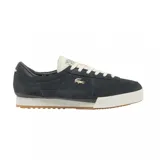 Championes Lacoste modelo Aura, color azul marino, confeccionados en gamuza con detalles en cuero. Presentan el logo del cocodrilo metálico en el lateral, cordones en tono crema y suela de goma con diseño dentado.