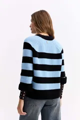 Buzo de punto con diseño de rayas horizontales anchas en color negro y celeste. Presenta cuello redondo, mangas largas y un corte holgado con terminaciones acanaladas.