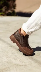 Bota de cuero color marrón chocolate, con cierre frontal con cremallera, costuras en contraste y suela track.