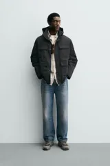 Parka técnica de corte relajado con interior ligeramente acolchado. Presenta cuello subido con capucha ajustable, cierre frontal con cremallera oculta por solapa con botones a presión, y cuatro bolsillos frontales de plastrón con solapa. Incluye cintura ajustable con cordón interior, puños con rib y aberturas laterales con cremallera en el bajo.
