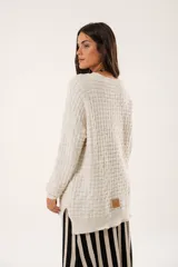 Buzo oversize color beige confeccionado en tejido sintético con destellos de lurex, cuello redondo y manga larga.