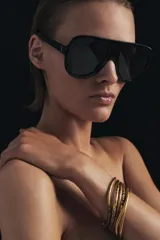 Pack de seis pulseras rígidas de metal dorado con acabado mate, algunas de ellas presentan incrustaciones de cristales oscuros en secciones específicas.