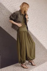 Pantalón globo de tiro alto color verde militar en tejido satinado con leve brillo. Presenta cintura elástica revestida, sección cruzada que se ata en un lateral con caída fluida y bajos elásticos ajustados.