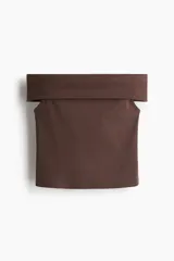 Top corto de punto acanalado color marrón oscuro, con escote ancho tipo bardot que deja los hombros descubiertos y corte ajustado.