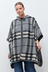 Capa abierta con capucha, diseño a cuadros en tonos grises, negros y beige. Presenta un cierre frontal tipo hebilla de cuero sintético en el cuello y mangas cortas tipo kimono.
