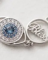 Pulsera de cadena fina con dije central en forma de ojo turco, decorado con cristales brillantes y detalles en azul. El diseño es delicado y sofisticado.