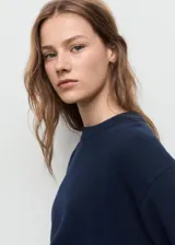 Sweater de punto medio en color azul marino, con cuello redondo y mangas largas. Presenta un diseño recto con terminaciones en canalé.