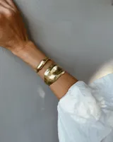 Brazalete rígido plateado con textura irregular.