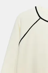 Jersey de punto de manga larga con cuello redondo, diseño en color azul marino con detalles de vivo en color blanco en el cuello y las costuras de las mangas.