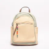 Mochila pequeña de material tejido tipo paja o rafia en color beige claro, con detalles en tejido de rayas verde menta y ribetes en cuero sintético marrón claro. Cuenta con un asa superior y un bolsillo frontal con cierre, adornado con un colgante de cuentas de colores (rosa, verde, naranja, azul).