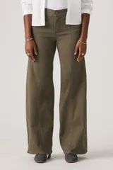 Pantalón de jean estilo wide leg en color verde oliva, con costuras verticales frontales que recorren el largo de las piernas. Presenta un diseño de tiro medio con cierre de botón y cremallera, y bolsillos laterales.