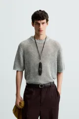 Camiseta de punto calado, color gris claro, de corte relajado (relaxed fit), con cuello redondo y mangas cortas.