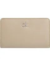 Billetera Calvin Klein Daily Medium color beige con logo CK metálico plateado en la parte delantera. Confeccionada en poliéster reciclado y poliuretano.