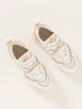 Zapatilla urbana color blanco con detalles en cuero color crema, con cordones y suela de goma.