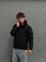 Campera puffer negra con diseño de paneles, cierre frontal completo y cuello alto. Presenta una textura diferenciada en la parte superior y bolsillos laterales.