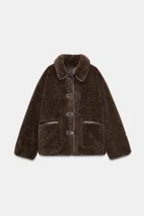 Chaqueta de cuello solapa y manga larga, con diseño de doble faz que combina tejido efecto ante y borreguillo. Cuenta con cierre frontal de botones y bolsillos delanteros.
