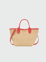 Bolso tipo tote pequeño de paja trenzada color natural, con ribetes y asas de cuero rojo. Presenta un logo bordado de dos caballos galopando en color rojo en el centro.