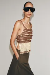 Top de crochet con escote recto y tirantes finos. Presenta un diseño bicolor con la parte superior en color marrón y la parte inferior decorada con abalorios en tonos crema y marrón.