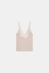 Top de punto canalé en color beige, con escote en pico adornado con una delicada aplicación de encaje blanco y tirantes anchos.