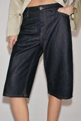 Bermuda de denim en color azul oscuro, de tiro medio con cintura con trabillas. Presenta costuras con pespuntes en color contraste, bolsillos laterales y cierre frontal con cremallera y botón metálico.