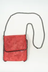 Bandolera de tamaño pequeño con solapa, confeccionada en material con efecto desgastado. Presenta bordes reforzados con costuras visibles y una cadena metálica oscura que funciona tanto como correa para el hombro como detalle decorativo en todo el contorno.