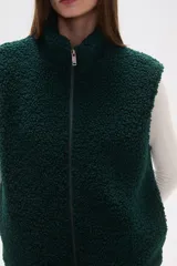 Chaleco sin mangas de textura peluche (teddy) color crema, con cuello alto y cierre frontal de cremallera.