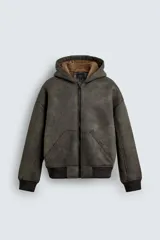 Cazadora relaxed fit de Zara confeccionada en tejido efecto piel con acabado lavado, interior de borreguillo a contraste, capucha, bolsillos de vivo en la cadera, acabados en rib y cierre frontal de cremallera.