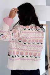 Saco de punto con diseño floral, cuello redondo y cierre frontal con botones. Presenta detalles de tejido calado en las mangas y puños acanalados. Incluye etiqueta de cuero sintético con la marca Amante.
