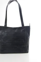 Cartera tipo tote de cuero vacuno negro con doble asa de hombro, panel superior liso y bolsillo exterior frontal con textura símil cocodrilo y costuras visibles en contraste.