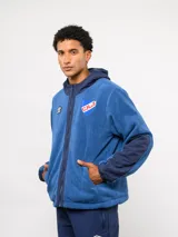 Campera de polar blanca con capucha y detalles en azul marino, con cierre frontal completo. Presenta el logo de Umbro y el escudo del Club Nacional de Football en el pecho.