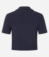 Blusa de cuello polo y manga corta, confeccionada en tejido rib de algodón con elastano. Presenta un diseño ajustado al cuerpo con escote en V y textura acanalada.