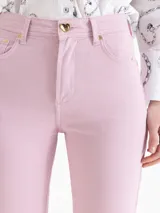 Pantalón Cuore de gabardina en tono gris cemento, con silueta ajustada en la cintura y pierna semi oxford con tajos laterales en el ruedo. Incluye botón metálico dorado con forma de corazón en el frente y pasadores.