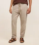 Pantalón masculino relaxed fit confeccionado en oxford de algodón, color beige, con trabillas en la cintura y cordón ajustable con lazo. Cuenta con bolsillos delanteros y traseros.