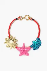Collar con cordón trenzado rojo y gris, cierre dorado y dijes colgantes de sol dorado, estrella de mar rosa con strass y concha marina azul y verde.