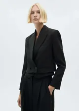 Chaqueta tipo blazer de corte crop, color negro, con cuello de solapa, cierre de doble botonadura y bolsillos de ribete.