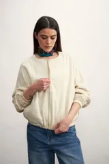 Chaqueta tipo bomber color negro, con cierre frontal metálico, cuello redondo y puños elásticos.