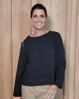 Remera de manga larga color blanco, con cuello redondo y dos bolsillos frontales tipo parche. Presenta un corte recto y holgado con un diseño minimalista.