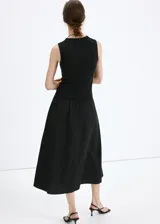 Vestido midi negro sin mangas, con cuello redondo alto y diseño combinado de cuerpo ajustado y falda amplia con vuelo.