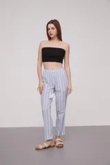 Pantalón babucha celeste con rayas verticales blancas, cintura elástica con cordón y detalle de borlas.