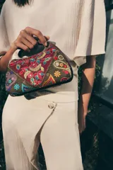 Bolso tipo caja con asa de mano rígida de madera, confeccionado con paneles de tela bordados con motivos florales, paisley y detalles en hilo metalizado.