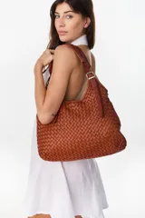 Cartera tipo hobo color suela, confeccionada en cuero con diseño trenzado y correa ajustable con hebilla metálica dorada.