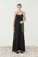 Vestido maxi negro de tirantes finos, con escote redondeado y diseño fluido y amplio con volado en la parte inferior.